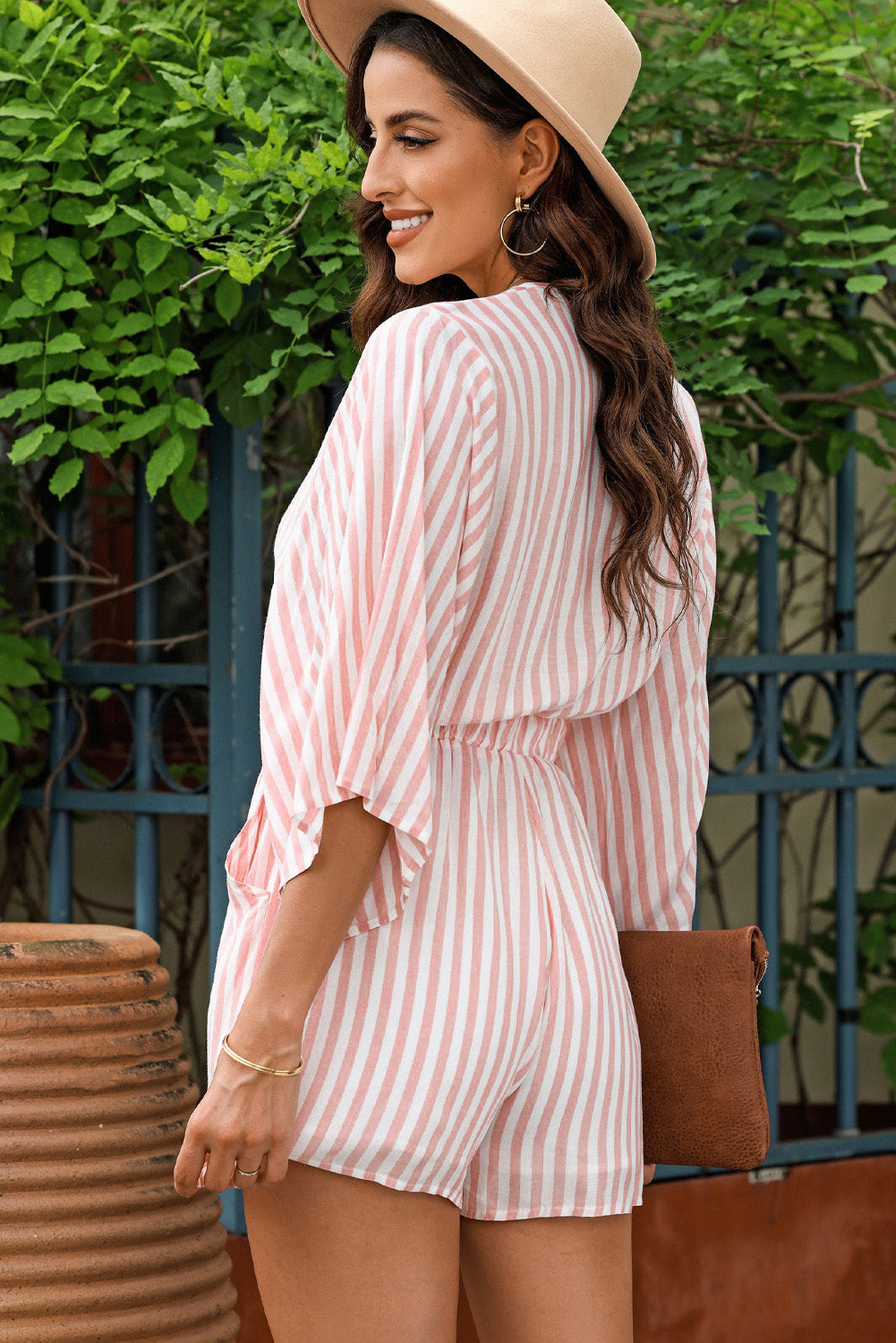 Striped tie-front kimono jumpsuit in blush pink with flutter sleeves and elastic waist.