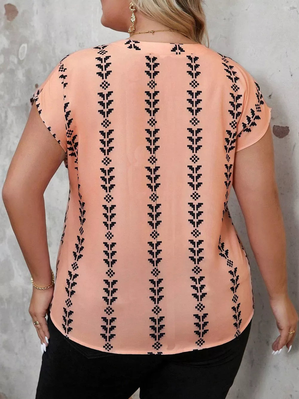Plus-size peach v-neck blouse with black geometric stripe pattern and short sleeves.