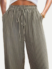 Wide-leg trousers in black and white vertical stripes with drawstring waist and pockets.