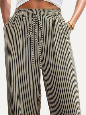 Wide-leg trousers in black and white vertical stripes with drawstring waist and pockets.