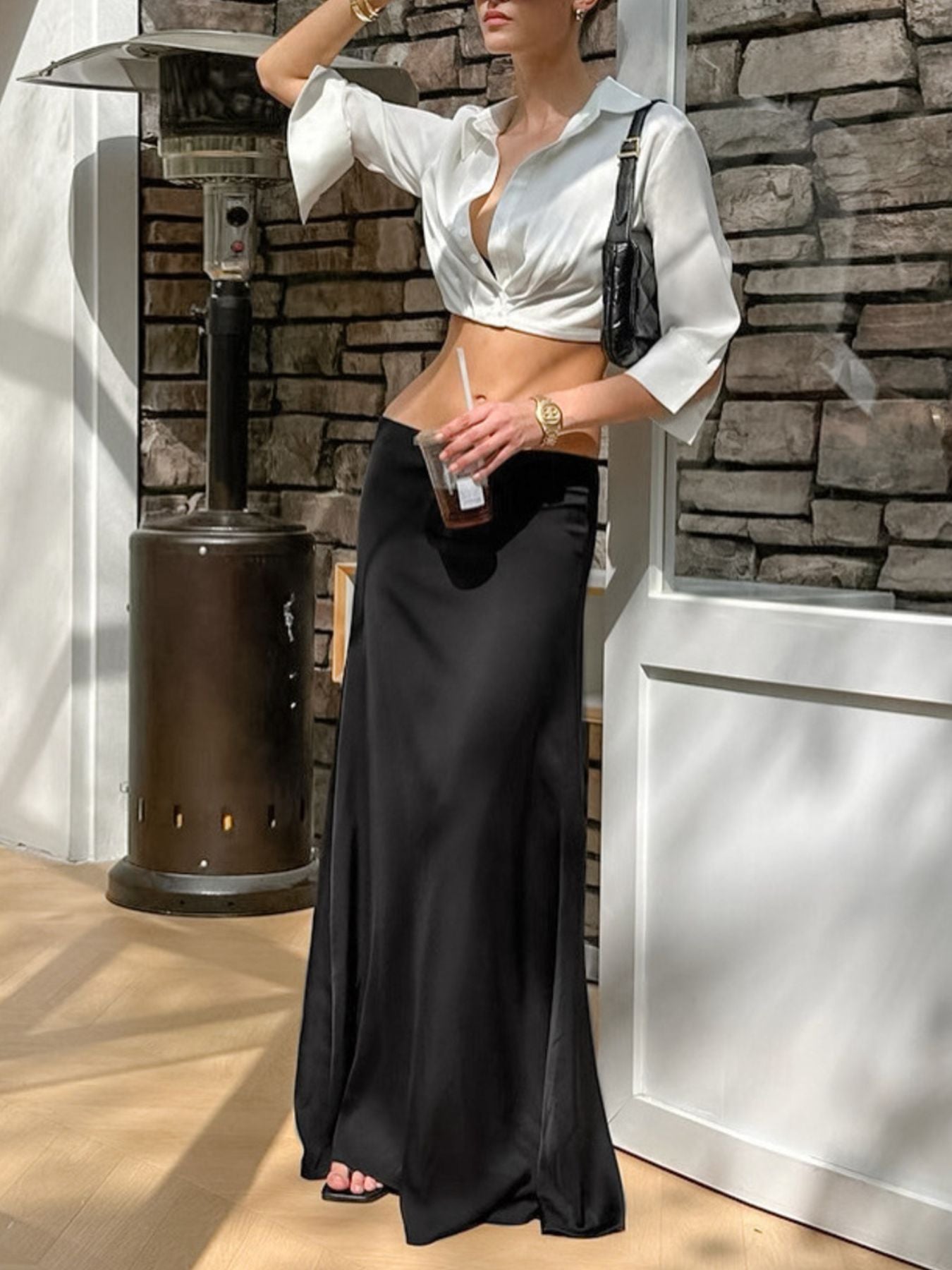 White collared button-up cropped shirt with wide sleeves, styled with a black maxi skirt.