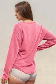 Pink ribbed long sleeve top with a crew neck, styled with light shorts.