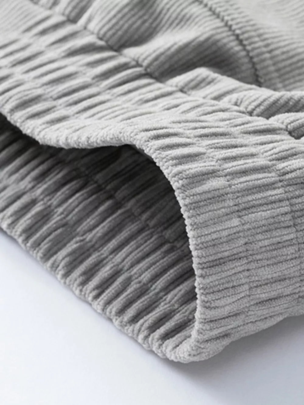 Grey corduroy trucker jacket detail showing textured fabric and seam.