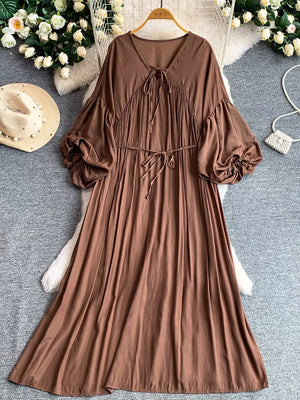 Brown bohemian maxi dress with balloon sleeves, v-neck, and tie waist.