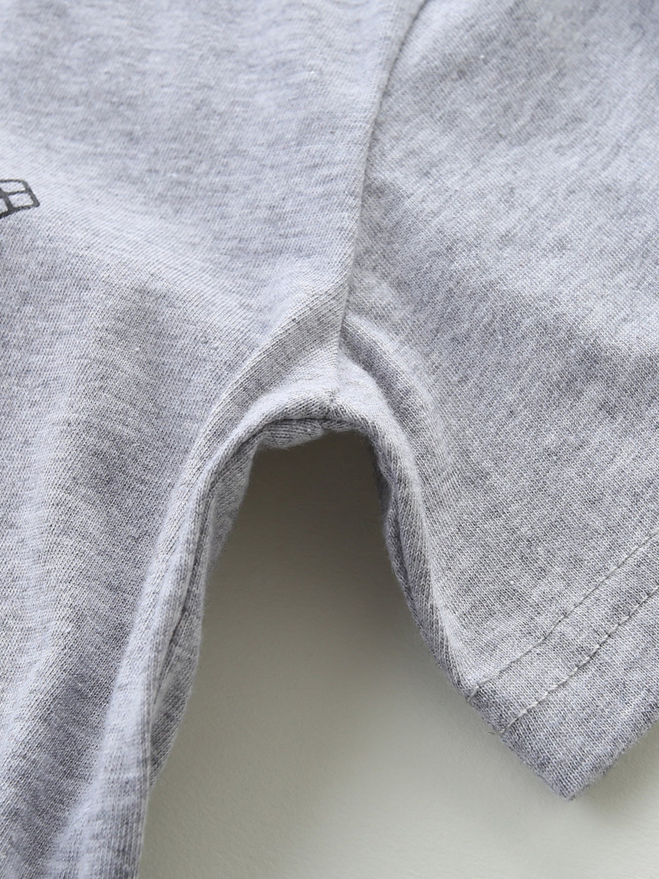 Toddler grey cotton t-shirt detail showing seams and a partial graphic.