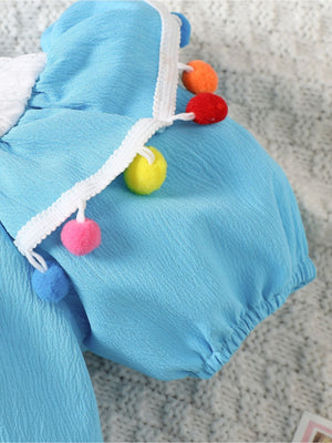 Pastel blue cotton baby romper with pom-pom trim and white lace detail.