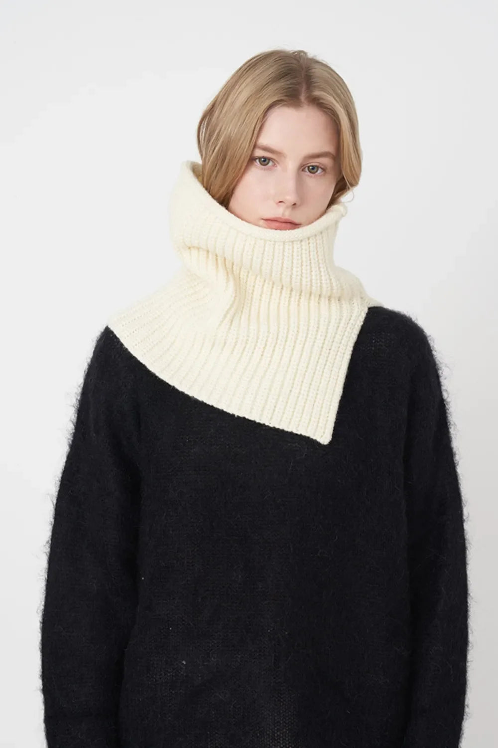 Ivory ribbed neck warmer with extended panel, worn over a black sweater.