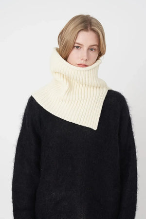 Ivory ribbed neck warmer with extended panel, worn over a black sweater.