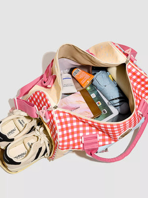 Charming gingham duffel bag with pink trim, filled with essentials like shoes, toiletries, and an umbrella.