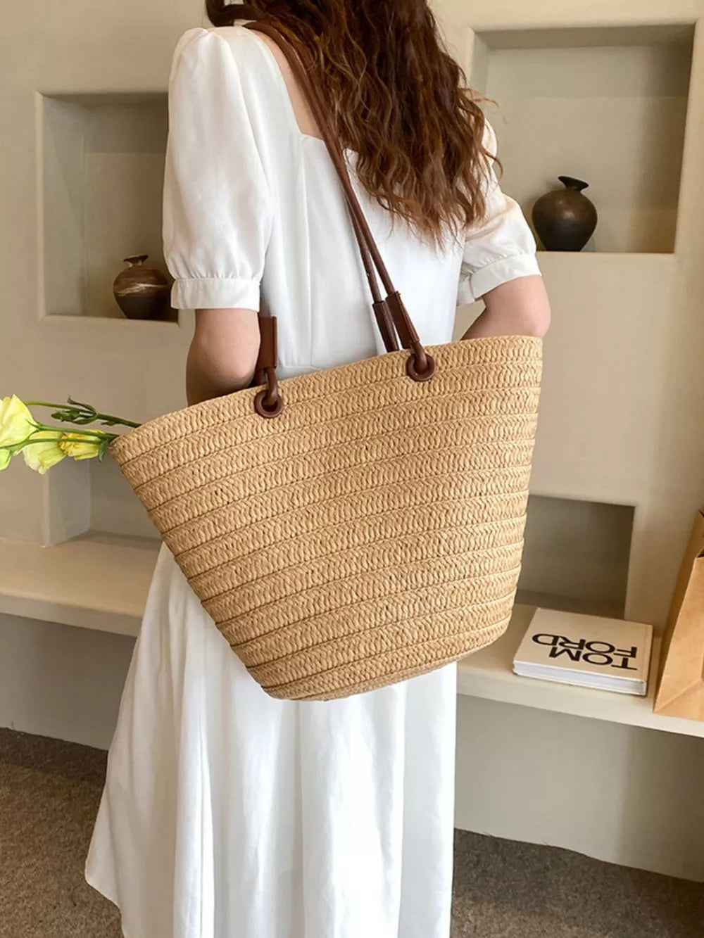 Natural straw woven large shoulder bag in khaki with brown leather straps.