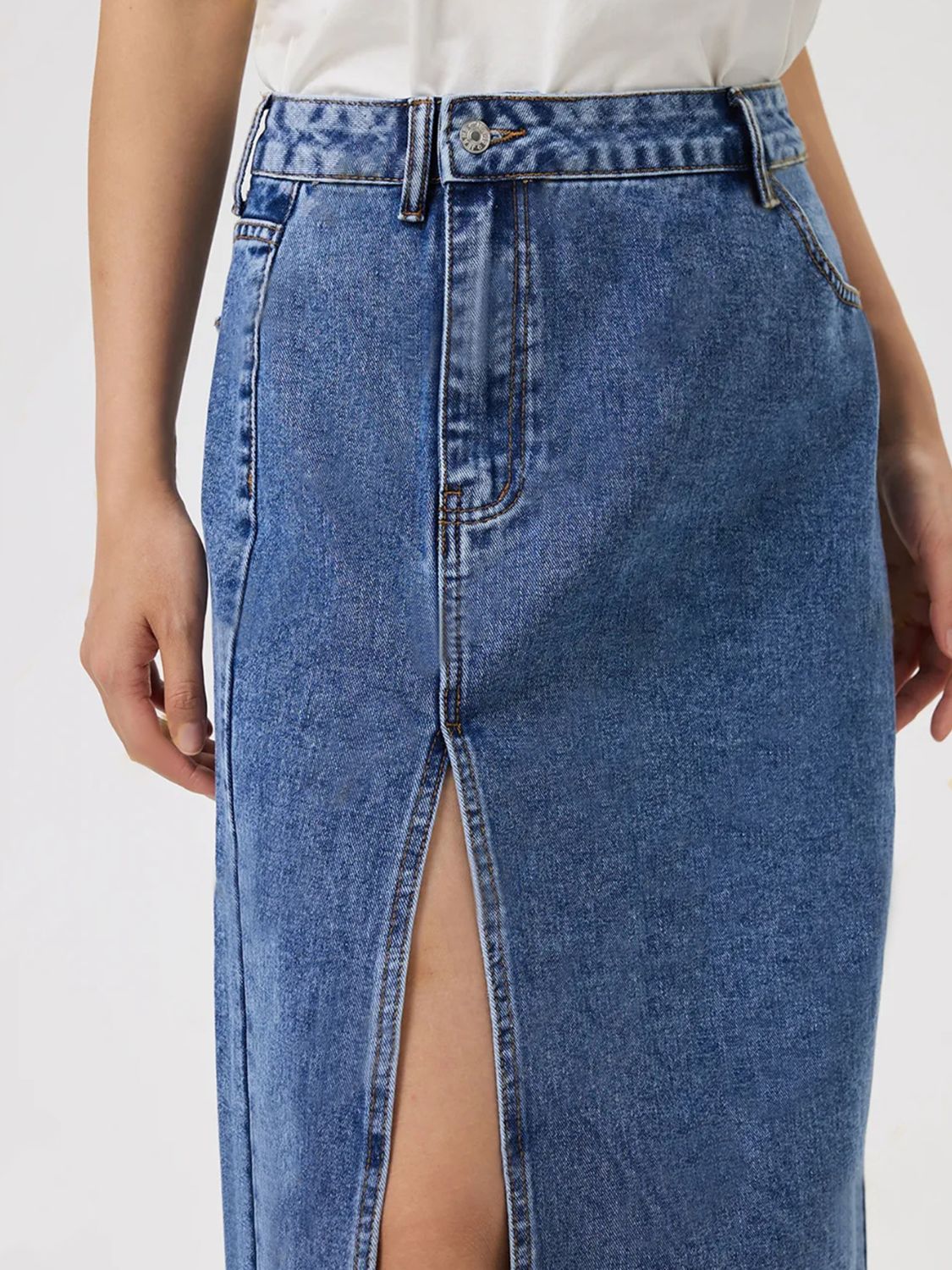 Medium wash denim midi skirt with a high slit and button-zip fly.