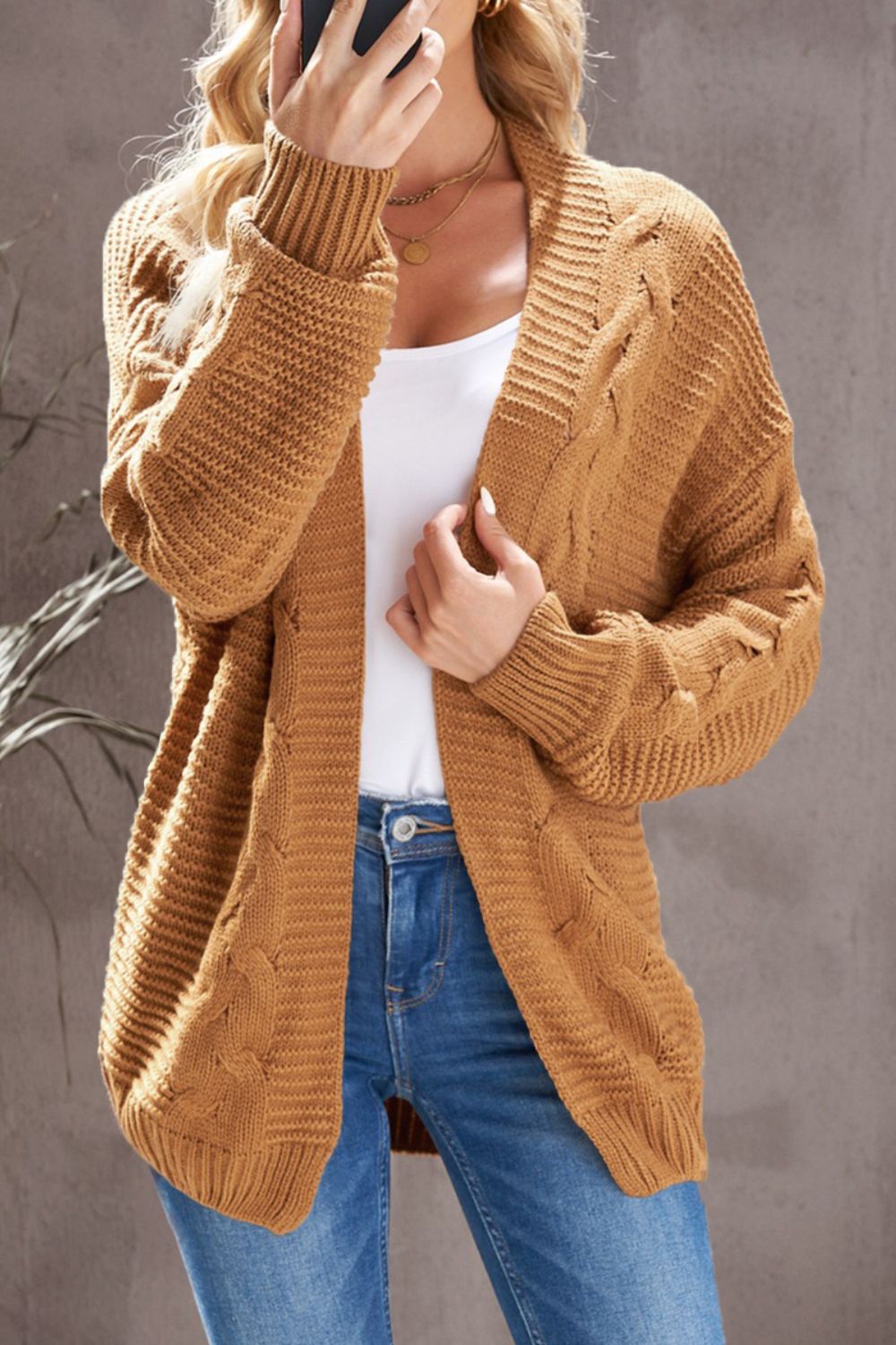 Camel cable knit open-front cocoon cardigan with textured sleeves.
