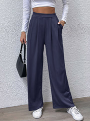 Navy pleated front wide leg trousers with pockets, styled casually.