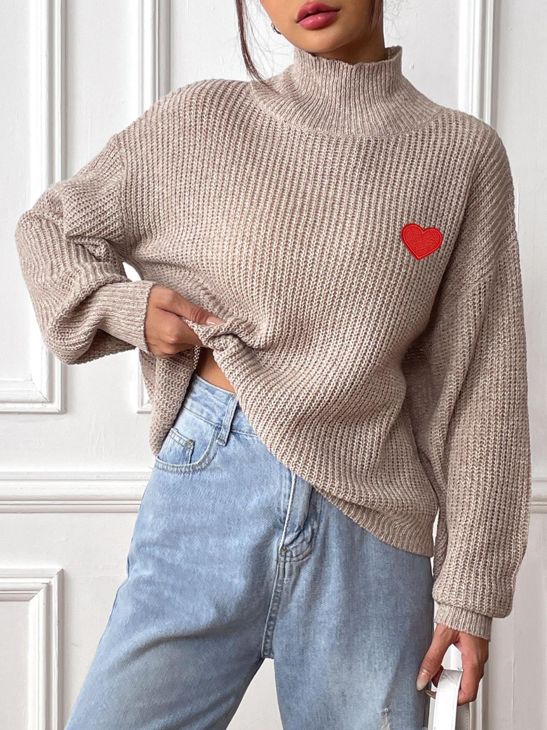 Khaki mock neck knit sweater with red heart appliqué and ribbed texture.