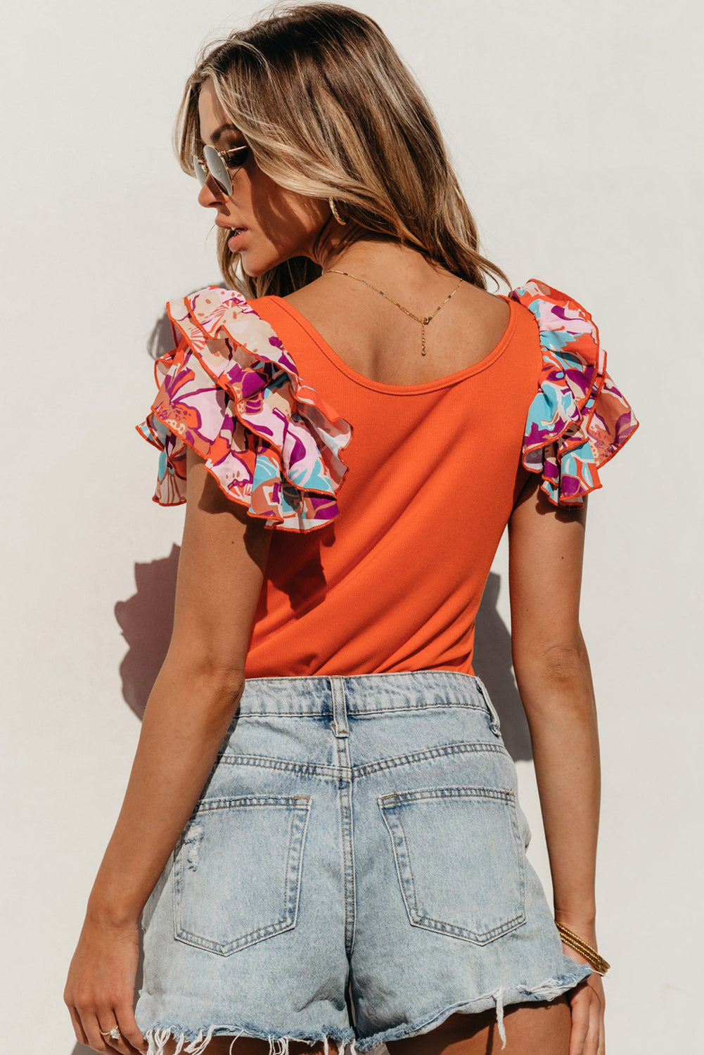 Orange-red ribbed bodysuit with floral ruffle sleeves and scoop neck.