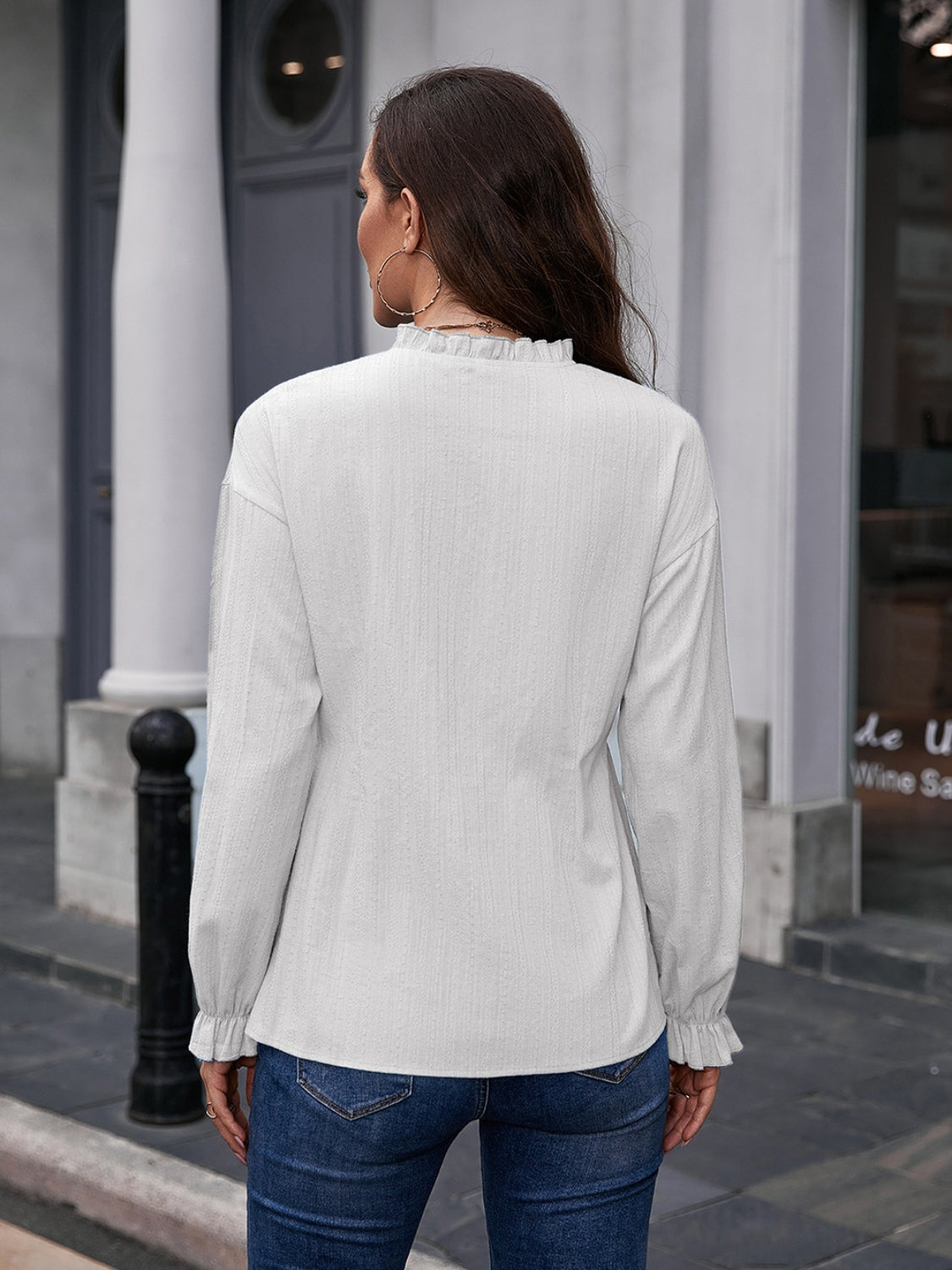 White textured ruffle collar peplum blouse with long sleeves and ruffled cuffs.