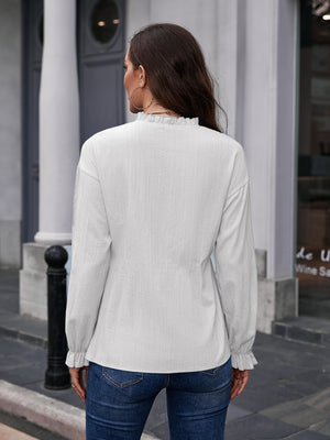 White textured ruffle collar peplum blouse with long sleeves and ruffled cuffs.