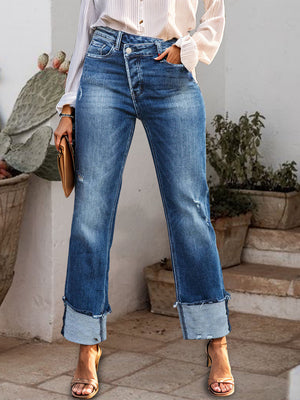 Medium wash cotton jeans with asymmetric waist, distressed details, and wide cuffs.