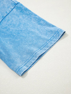 Mineral washed blue cotton t-shirt with crew neck and short sleeves, showing sleeve hem detail.