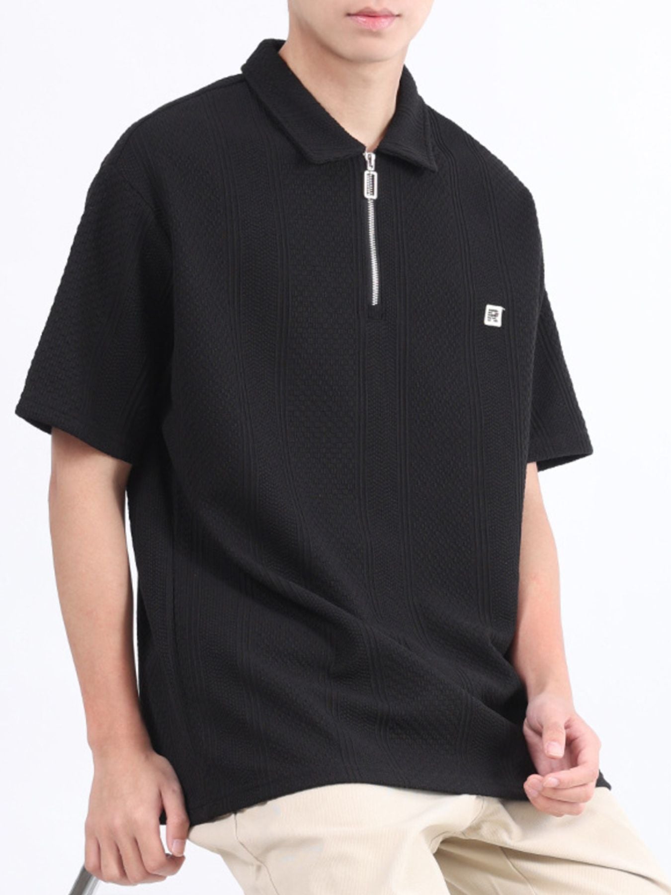 Black textured polo shirt with short sleeves and a zipper detail