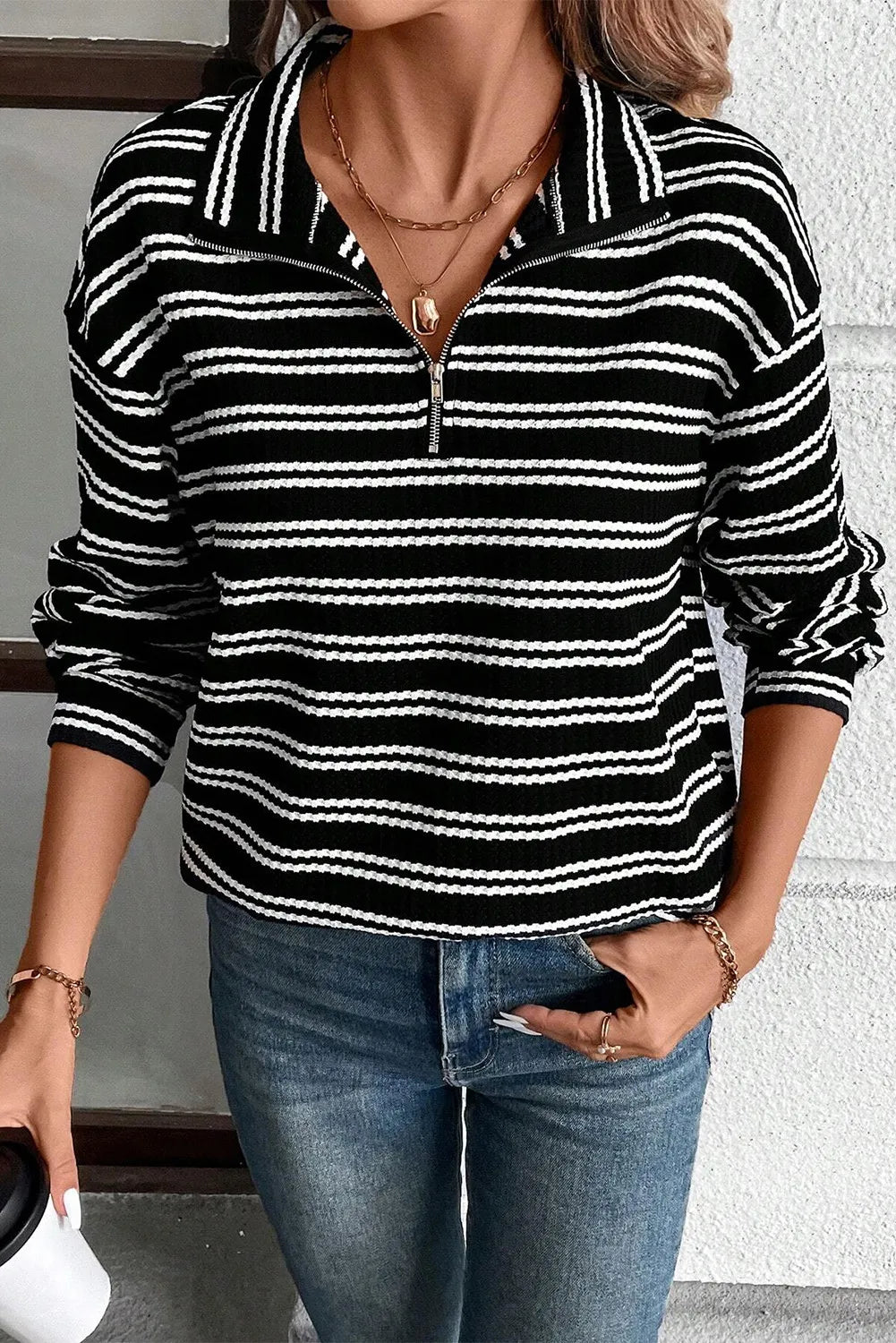Black and white striped ribbed half-zip pullover sweater with a collar.