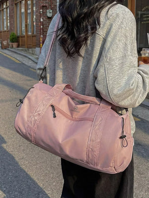 Pink nylon travel bag with front zipper pocket and adjustable shoulder strap