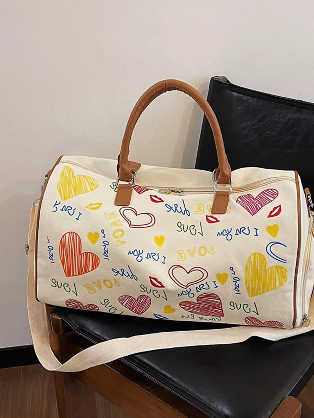 Vibrant canvas duffel bag with colorful heart and lip print, brown trim, and adjustable strap.