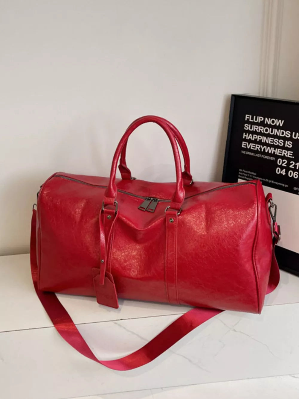 Textured metallic duffle bag in wine red with detachable strap and dual handles.
