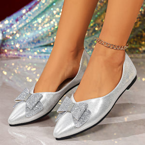 Silver pointed toe flats with glitter bows and a chain anklet.
