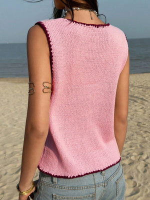 Pink knit sweater vest with contrast trim and scalloped hem.