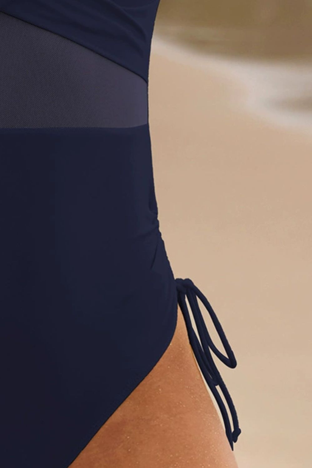 Dark navy one-piece swimsuit with mesh panels and adjustable side ties.