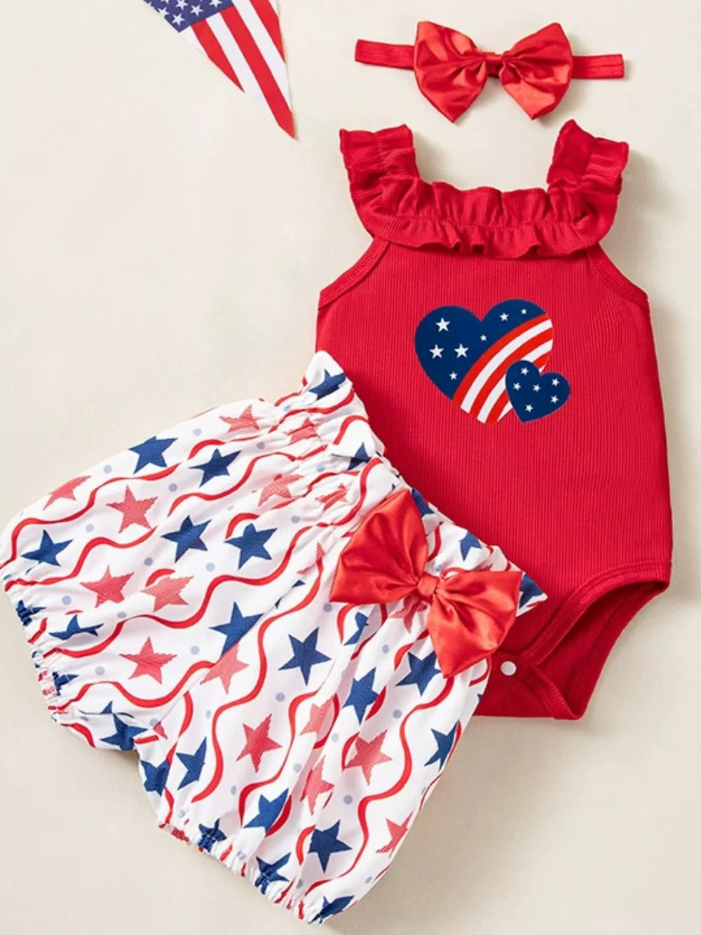 Red patriotic baby set with ruffled neckline, heart graphic, and star print bloomer shorts with bow.