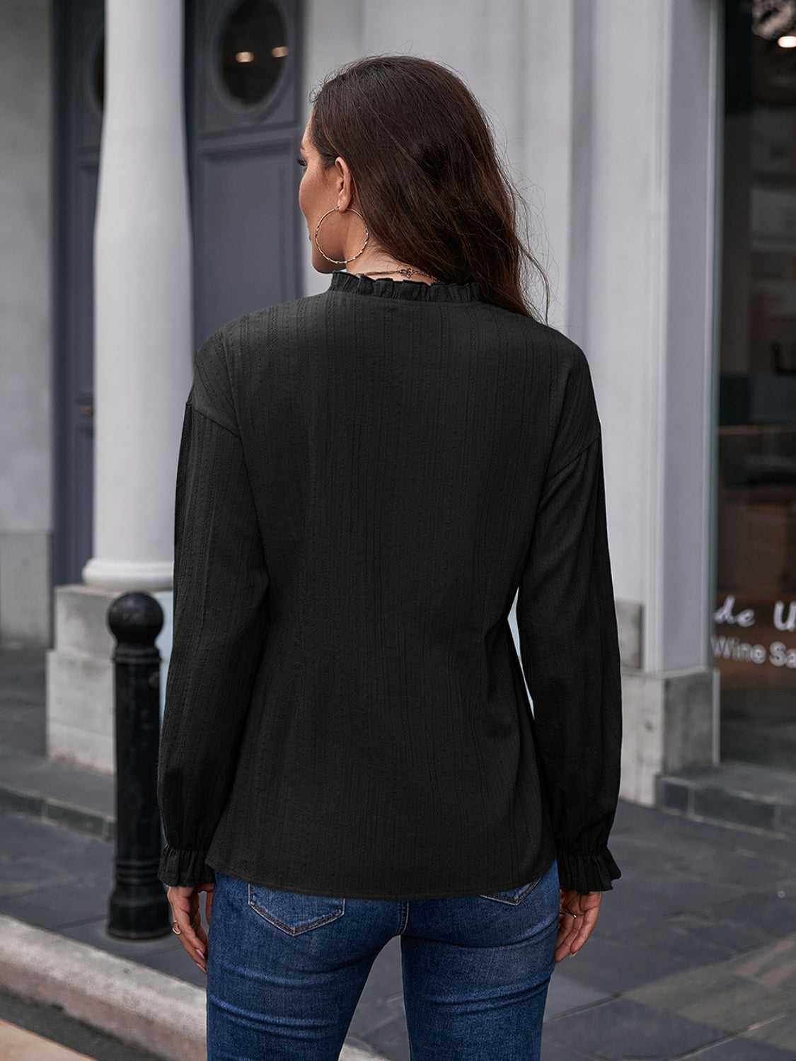Black textured ruffle collar peplum blouse with long sleeves and ruffled cuffs.