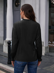 Black textured ruffle collar peplum blouse with long sleeves and ruffled cuffs.