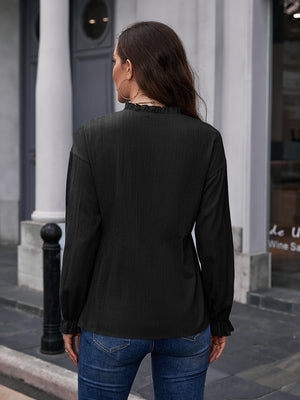 Black textured ruffle collar peplum blouse with long sleeves and ruffled cuffs.