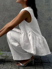 White sleeveless peplum top and wide-leg pants set in cotton, styled with silver heels.