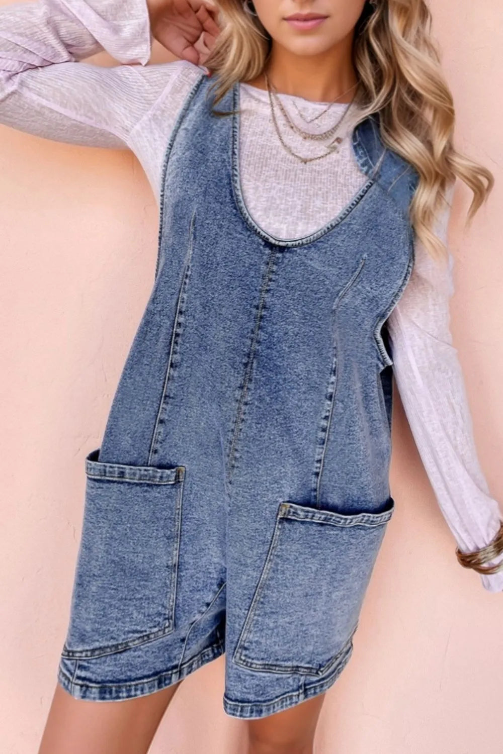 Acid wash denim romper with patch pockets and a U-neckline.