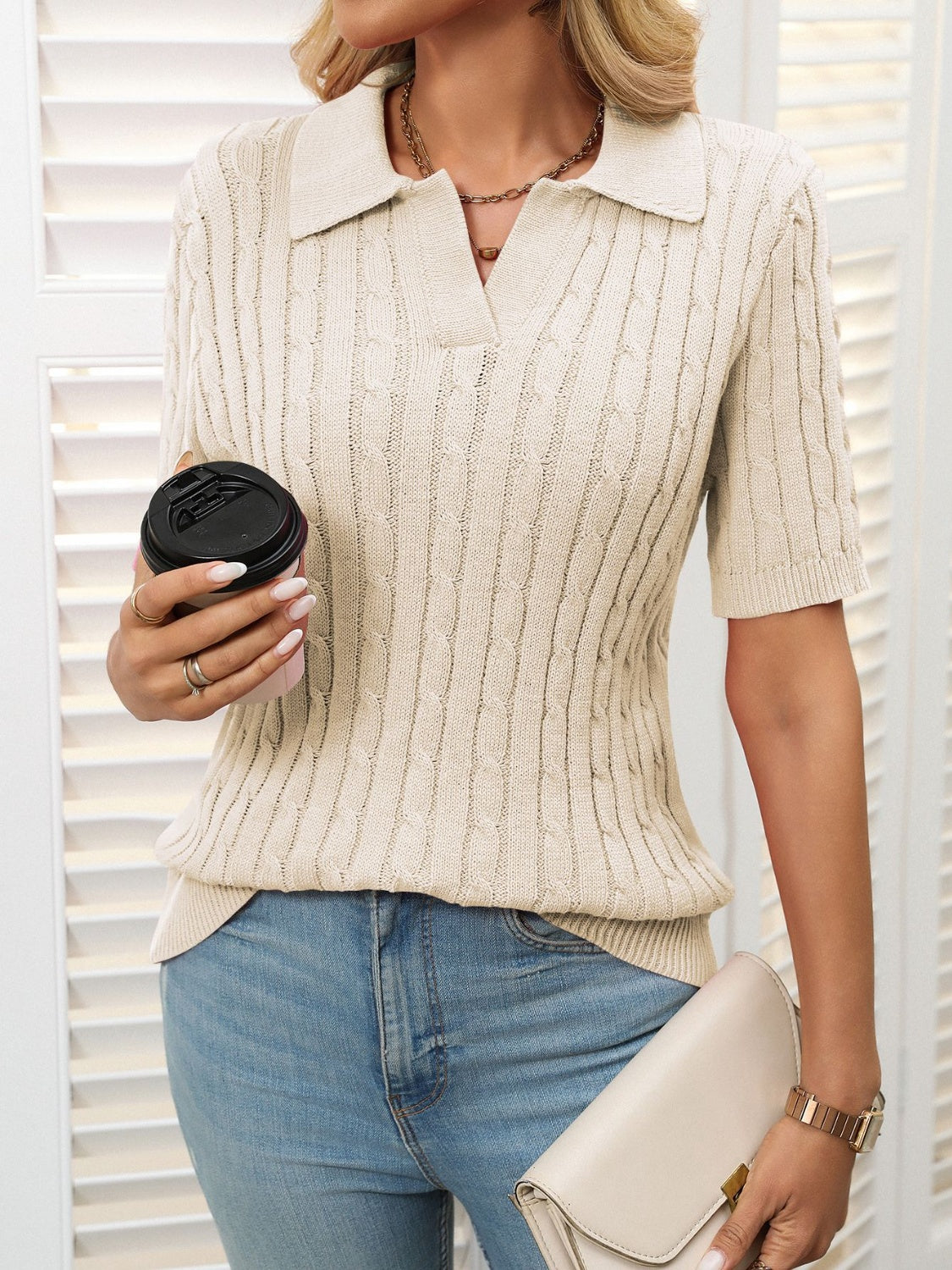 Beige cable knit polo sweater with short sleeves and a collar.