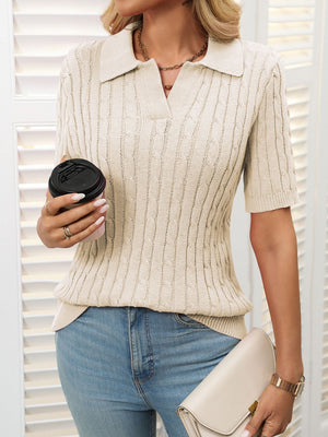 Beige cable knit polo sweater with short sleeves and a collar.