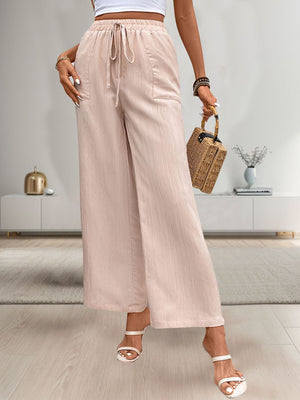 Apricot linen drawstring palazzo pants with pockets and wide legs.