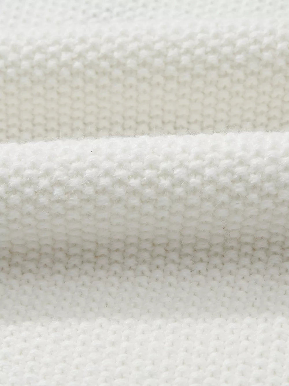 White chenille chunky knit sweater with crew neck, showing fabric texture.
