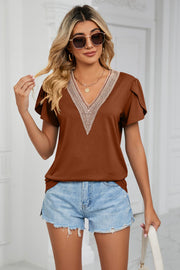 Brown V-neck blouse with lace trim and flutter sleeves, styled with denim shorts.