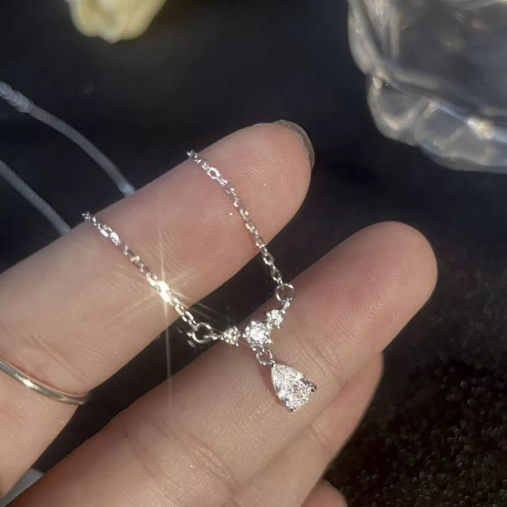 Silver necklace with delicate chain and teardrop zircon pendant, accented with small stones.