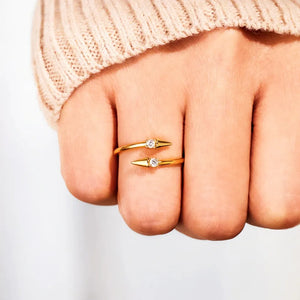 Gold bypass ring with two pointed ends, each set with a cubic zirconia stone.