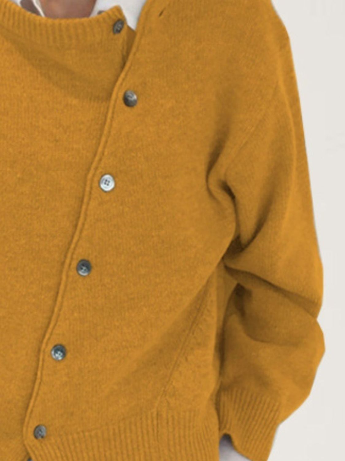 Mustard yellow acrylic knit cardigan with asymmetric button-up front and ribbed cuffs.
