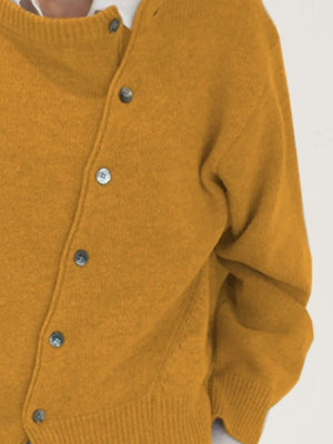 Mustard yellow acrylic knit cardigan with asymmetric button-up front and ribbed cuffs.