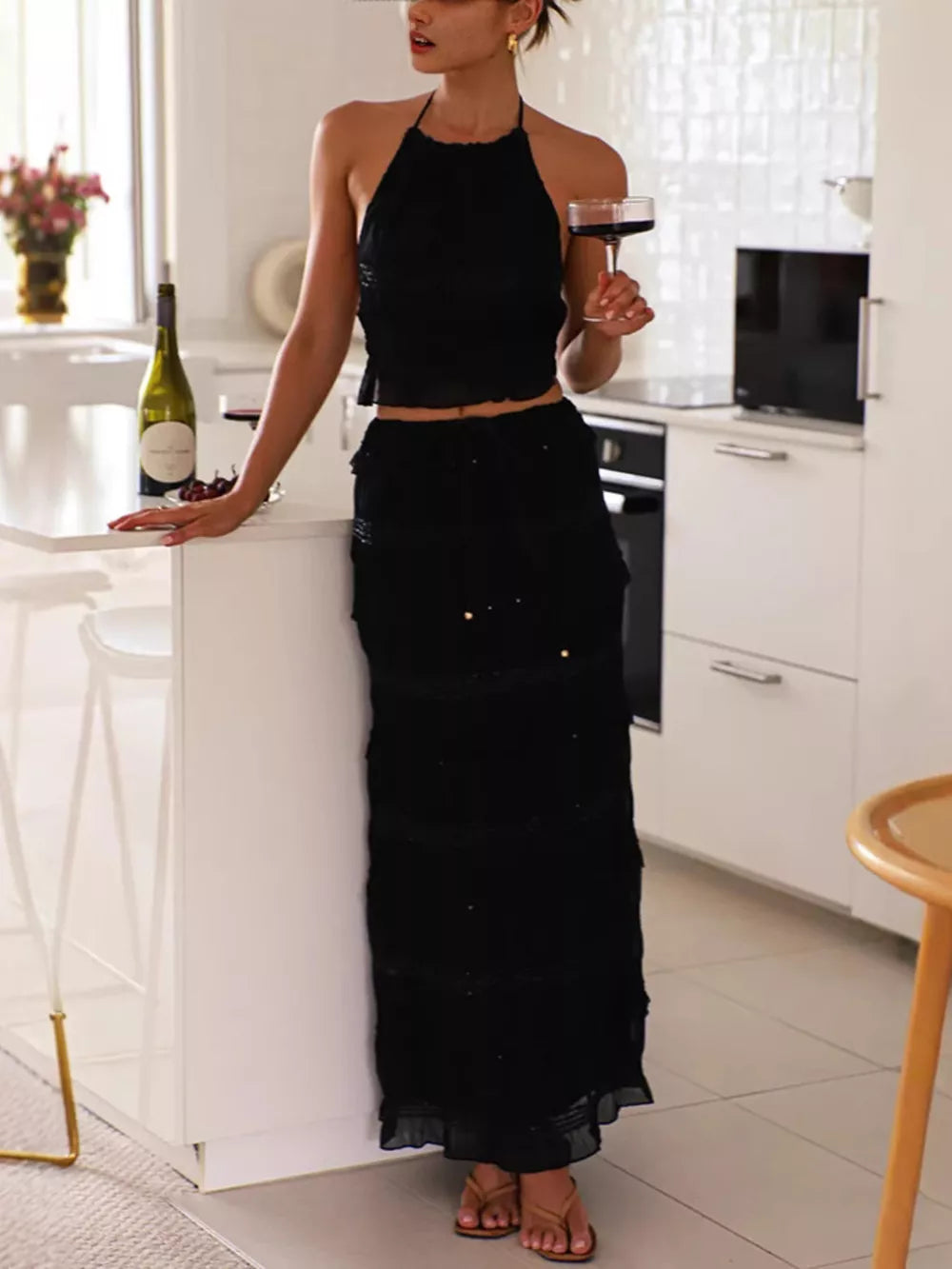 Black halter neck smocked two-piece ensemble with tiered skirt.