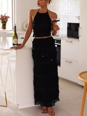 Black halter neck smocked two-piece ensemble with tiered skirt.