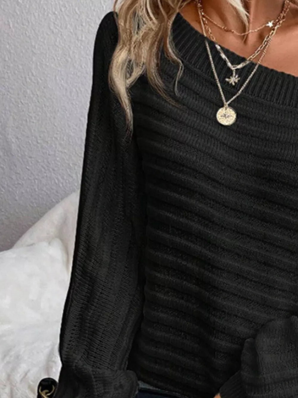 Black ribbed knit one-shoulder sweater with long sleeves.
