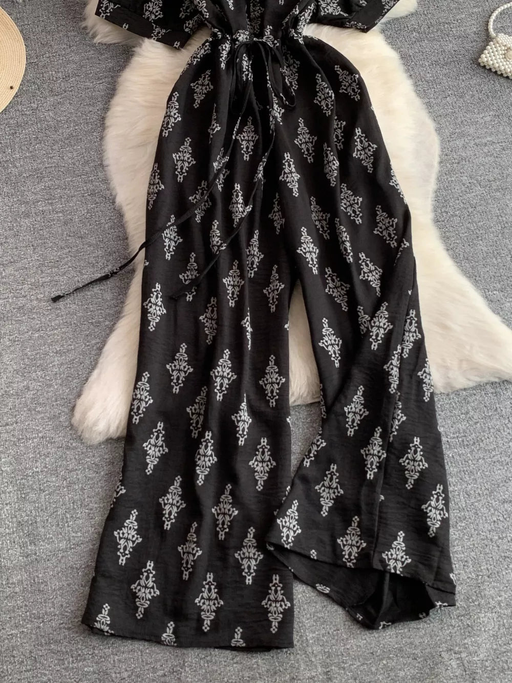 Black patterned jumpsuit with drawstring waist and wide legs.